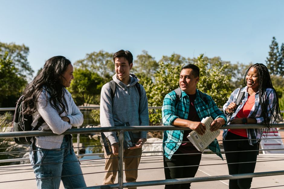 A diverse group of happy college students socializing on a sunny day outdoors.