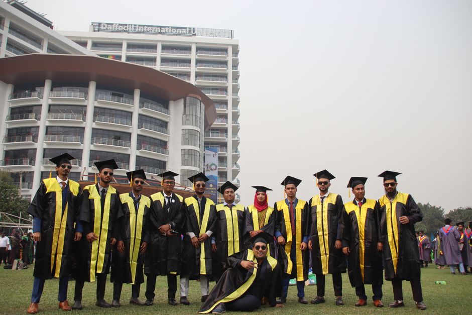 Graduating students celebrating with friends in front of university building.