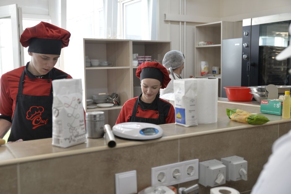 Young culinary students practicing in a professional kitchen setting for a cooking class.