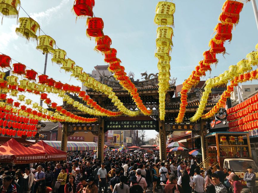 Crowd enjoying a colorful lantern festival at a traditional temple, showcasing vibrant decorations and cultural elements.