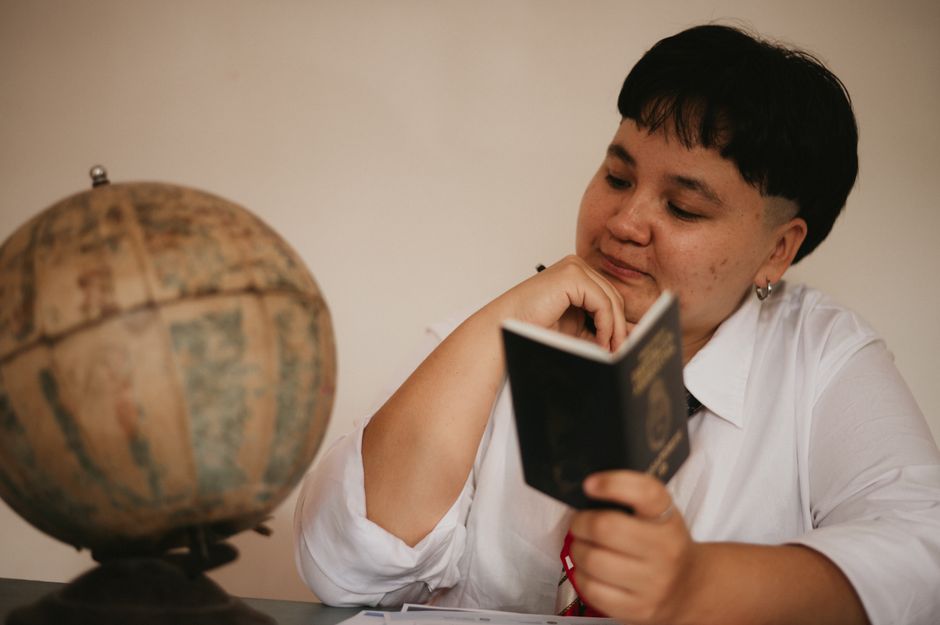 A pensive young adult reading a passport next to a vintage globe, symbolizing travel dreams.